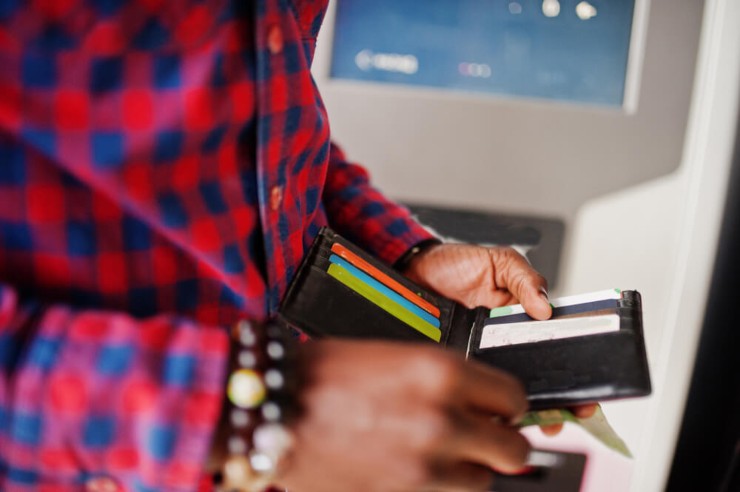 Ragazzo al bancomat che tira fuori la carta