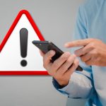 Uomo che indica lo smartphone e segnale di attenzione, pericolo